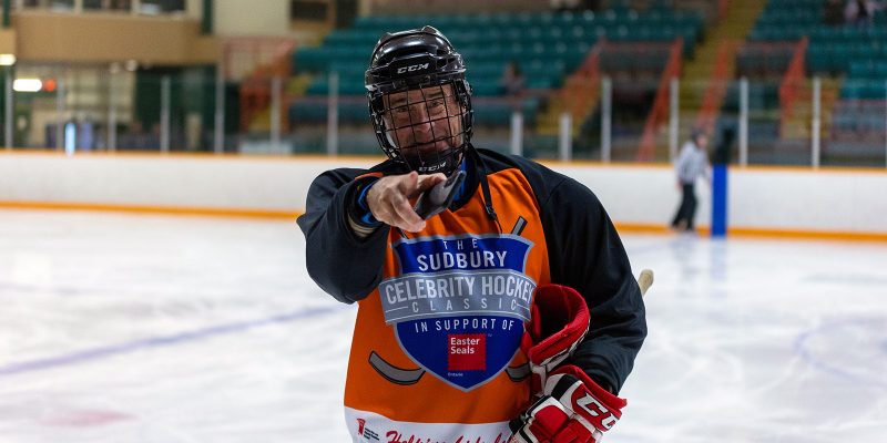 A Sudbury player on the ice points to the camera.