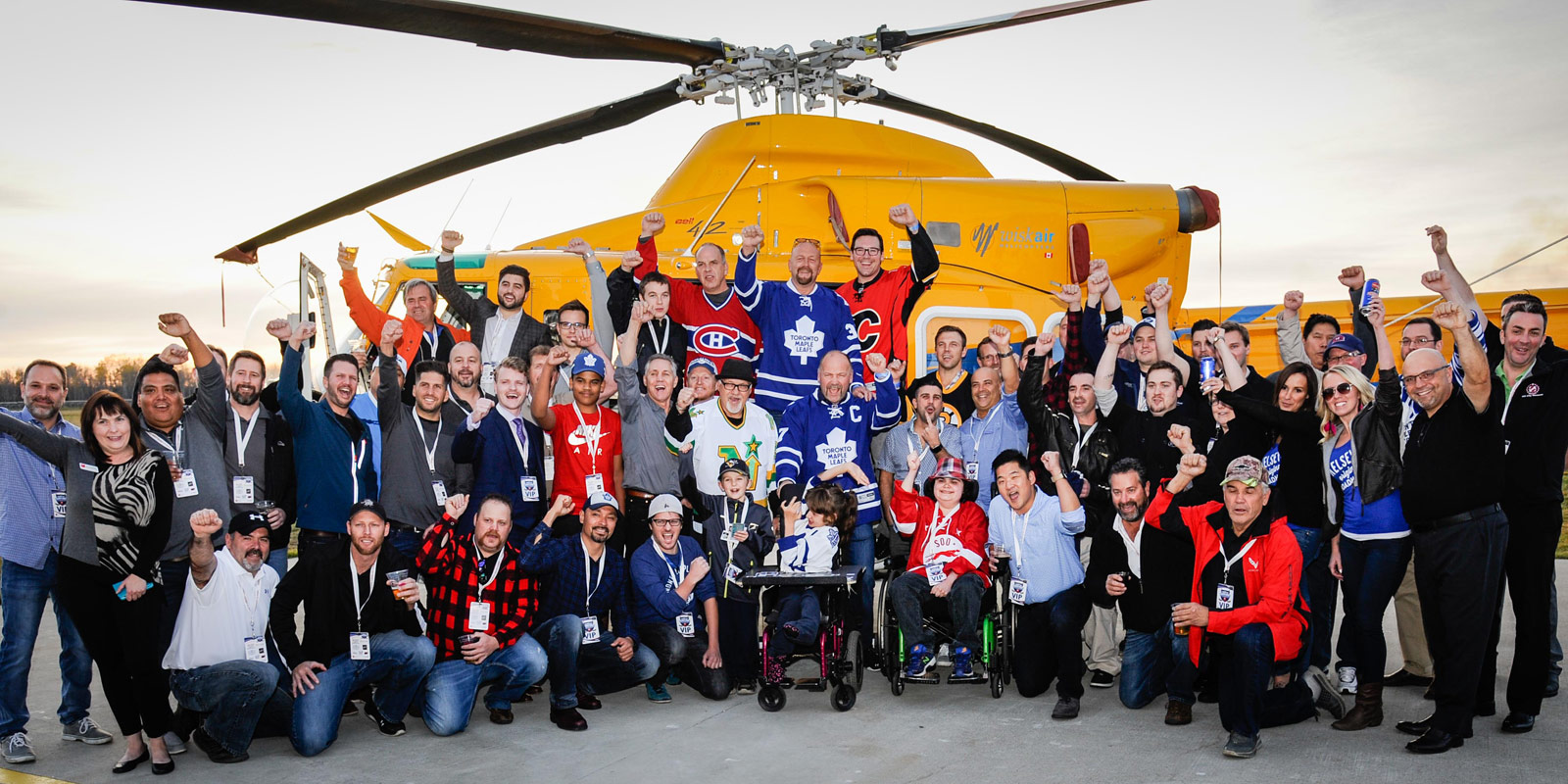 Everyone at the draft party poses infront of a yellow helicopter